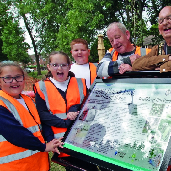 Group of adults and children in high vis jackets in woodlands