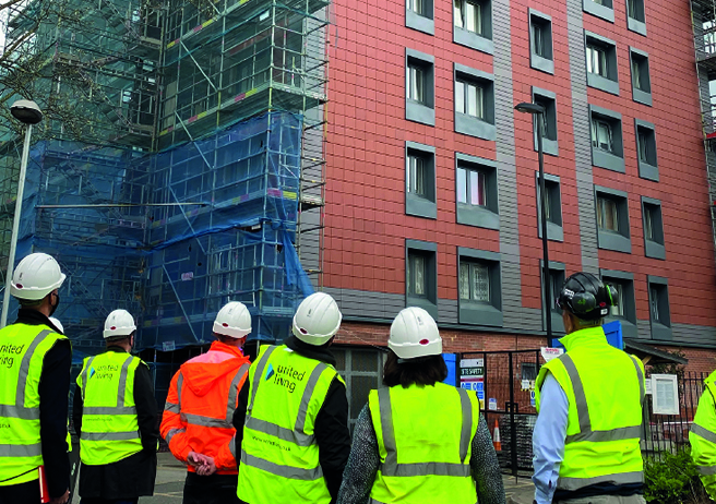 site workers observing building with new cladding and scaffolding