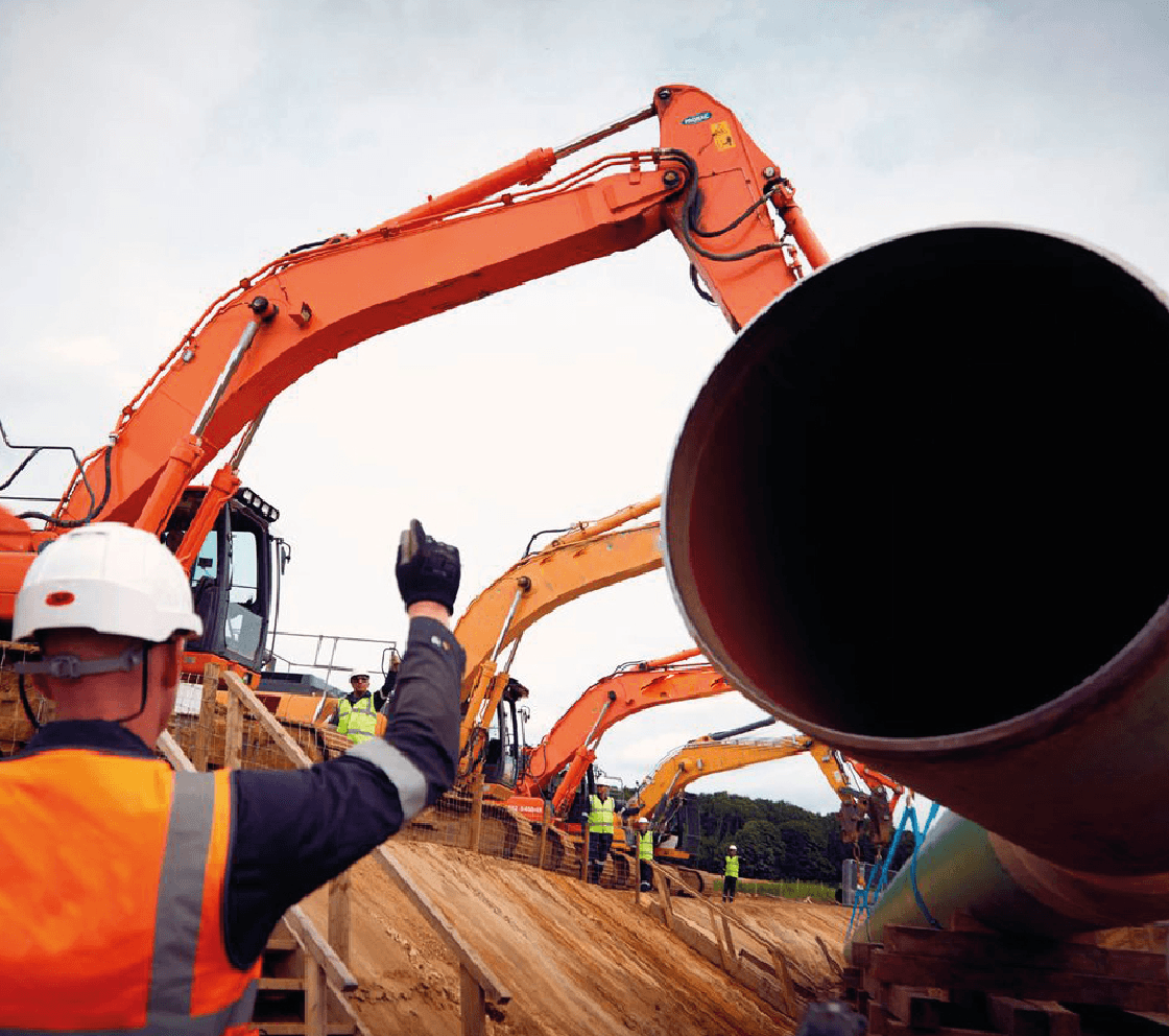 cranes lowering gas pipes into ground