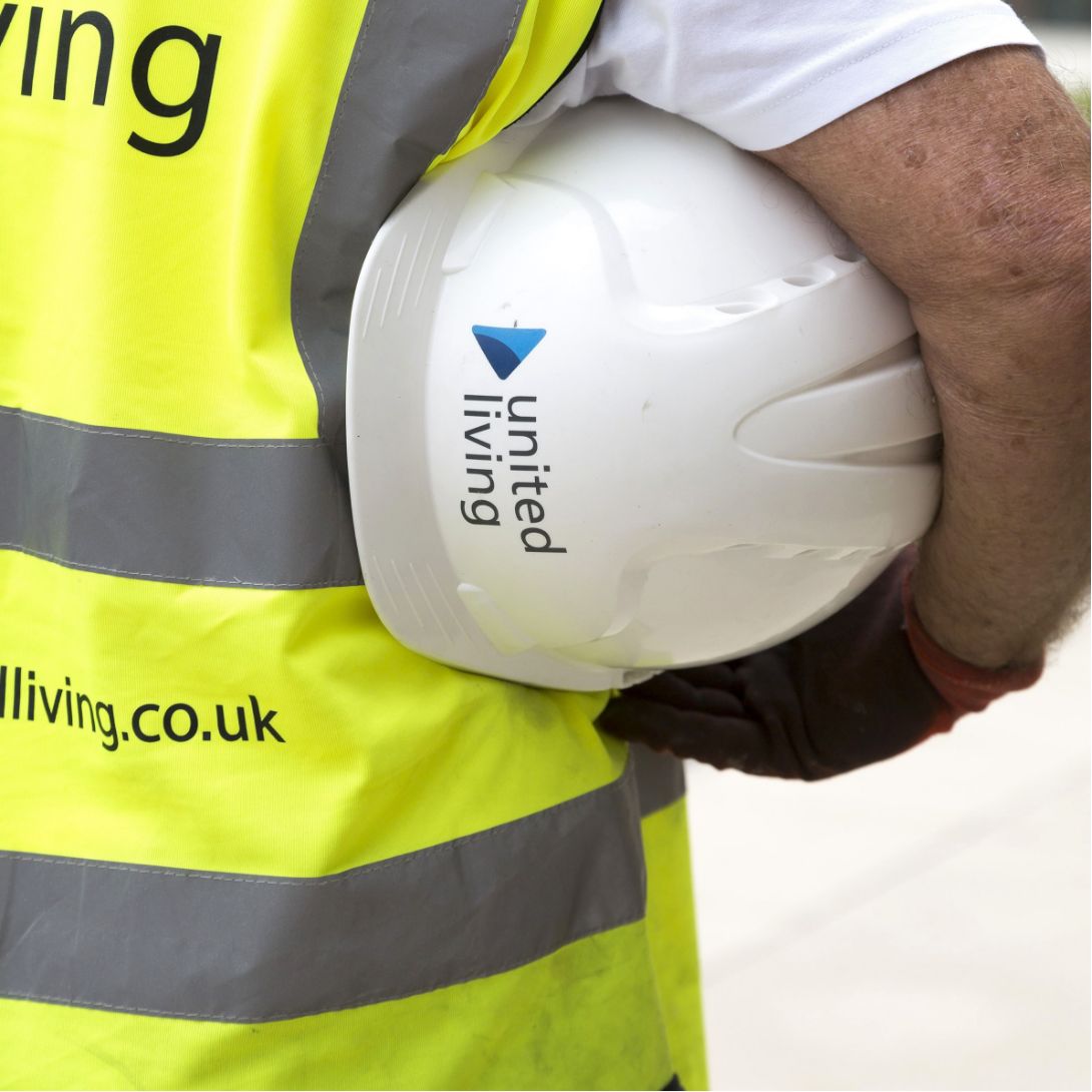 Construction worker holding United Living hard hat