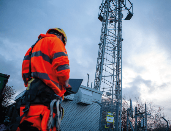 Construction worker stood below a telecommunications tower