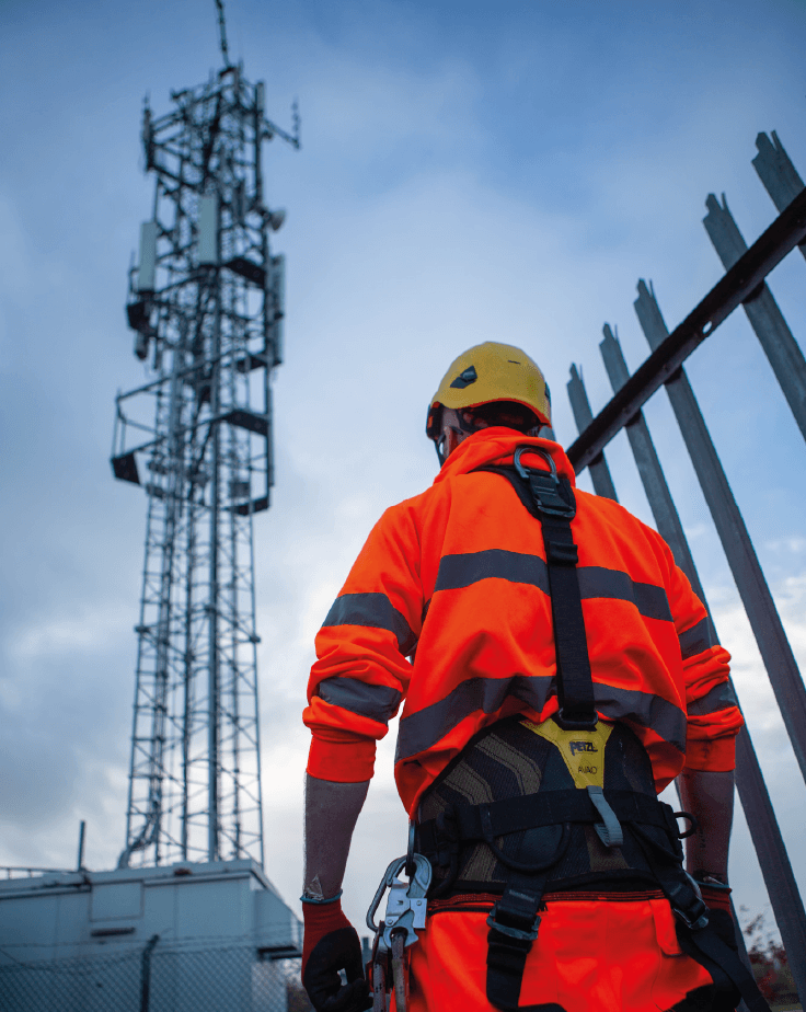 Construction worker standing below a telecommunications tower