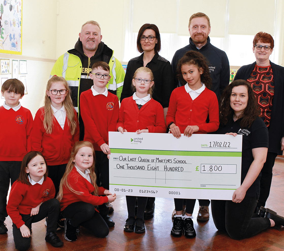 group of teachers and school children holding a large cheque