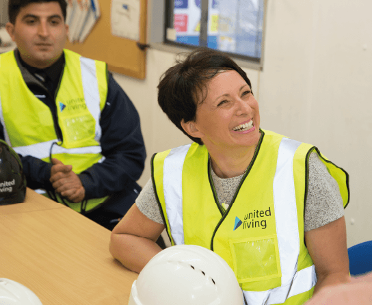 United Living employee sat at a table laughing with a colleague