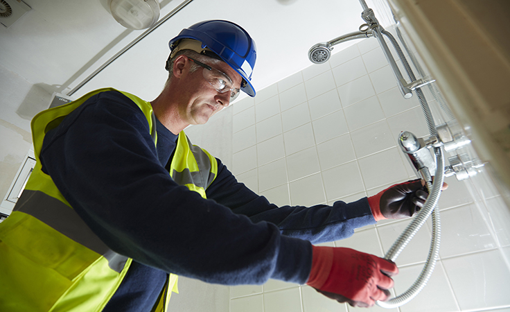 employee fitting new shower to resident home