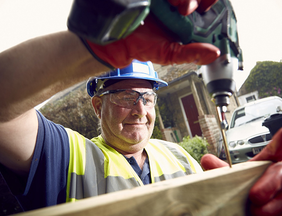 construction worker drilling outdoor fence