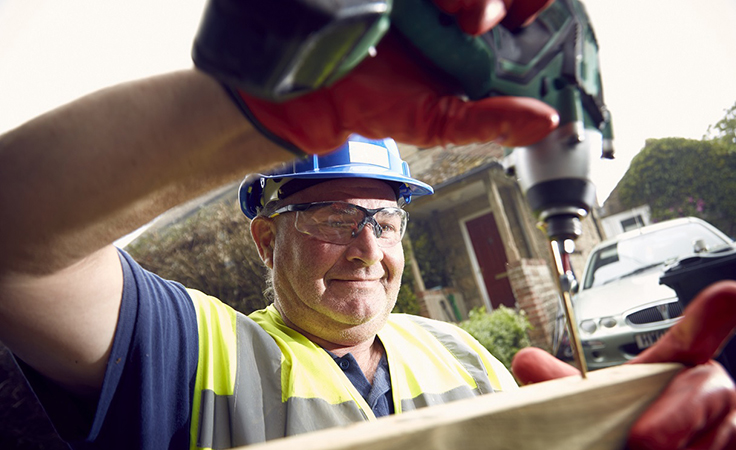 construction worker drilling outdoor fence