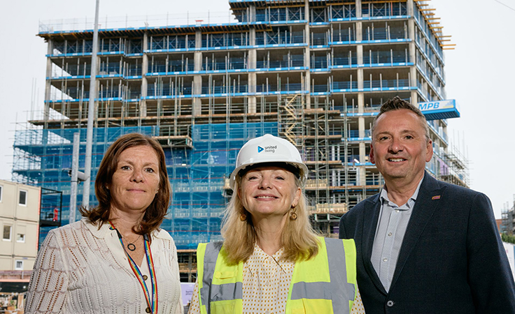 group of 3 people standing in front of building being built