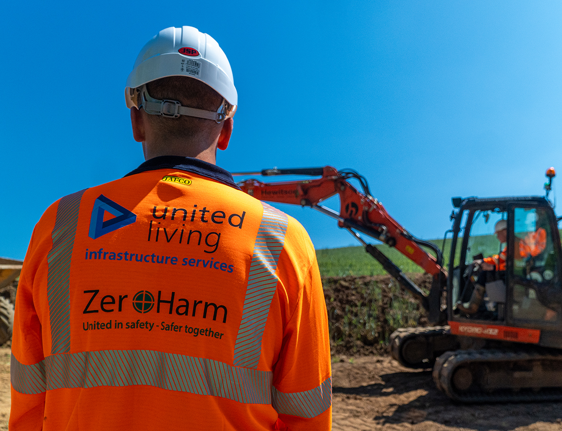 construction worker standing in front of digger