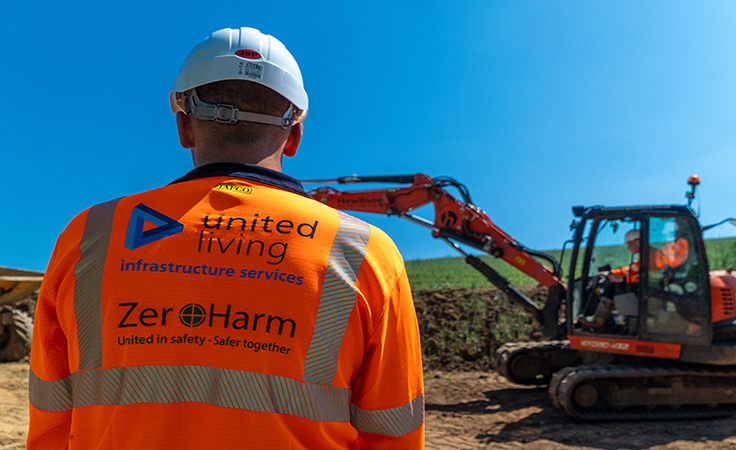 construction worker standing in front of digger