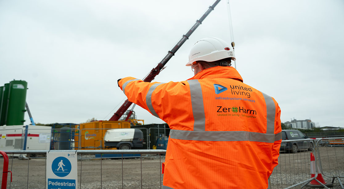 construction worker in PPE pointing towards crane